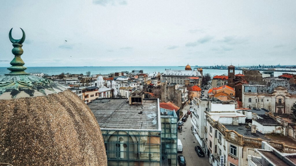 View of Constanța’s old town rooftops with domes, minarets, and the Black Sea in the background, seen from an elevated vantage point in Constanța, Romania.