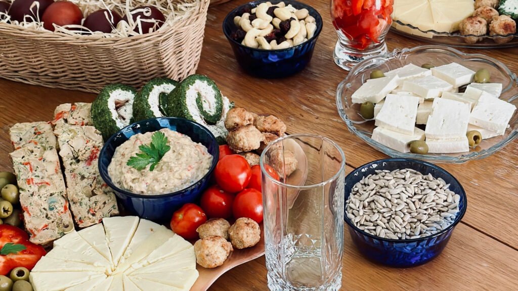 Traditional Romanian Easter cold platter with eggplant salad, cheeses, drob, olives, and decorated boiled eggs, displayed on a wooden table in Romania.